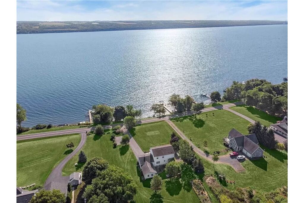 A residential area with a large body of water, houses, and a road.