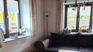 A cozy living room with a wooden ceiling, a leather sofa, a small wooden table, and a fur rug on the floor.