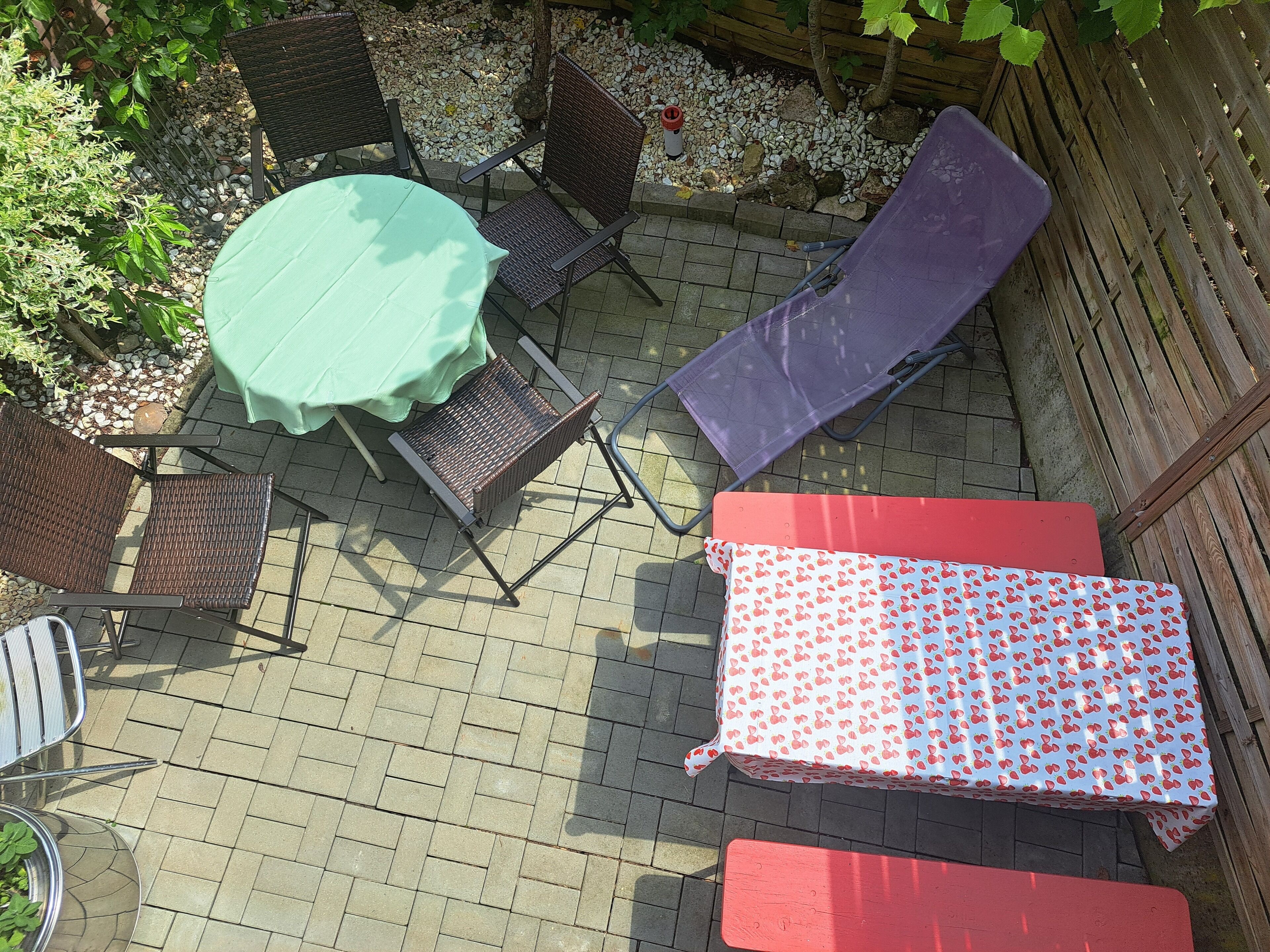 An outdoor patio with a round table, two chairs, a bench, and a covered area.
