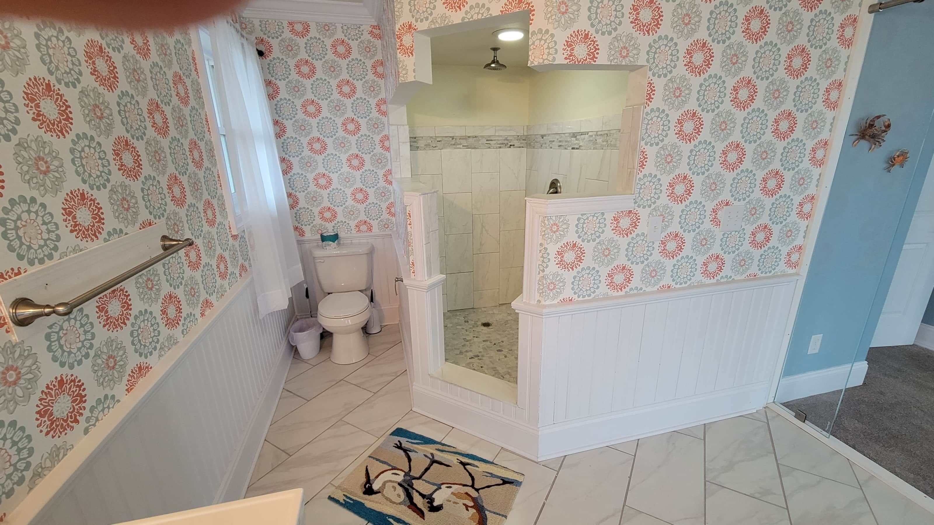 A bathroom with a shower, toilet, and a patterned wall.
