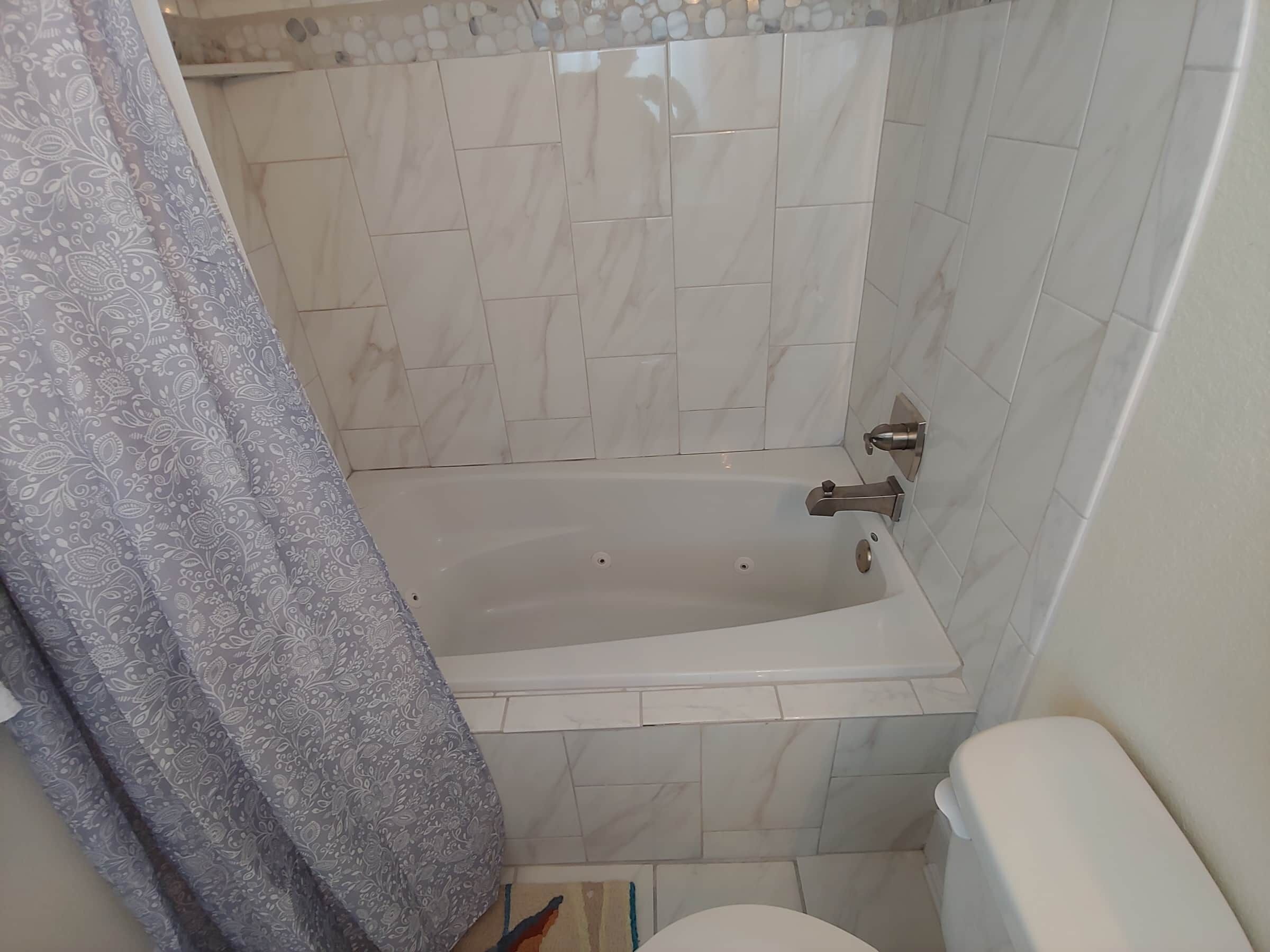 A bathroom with a bathtub, toilet, and a shower curtain.