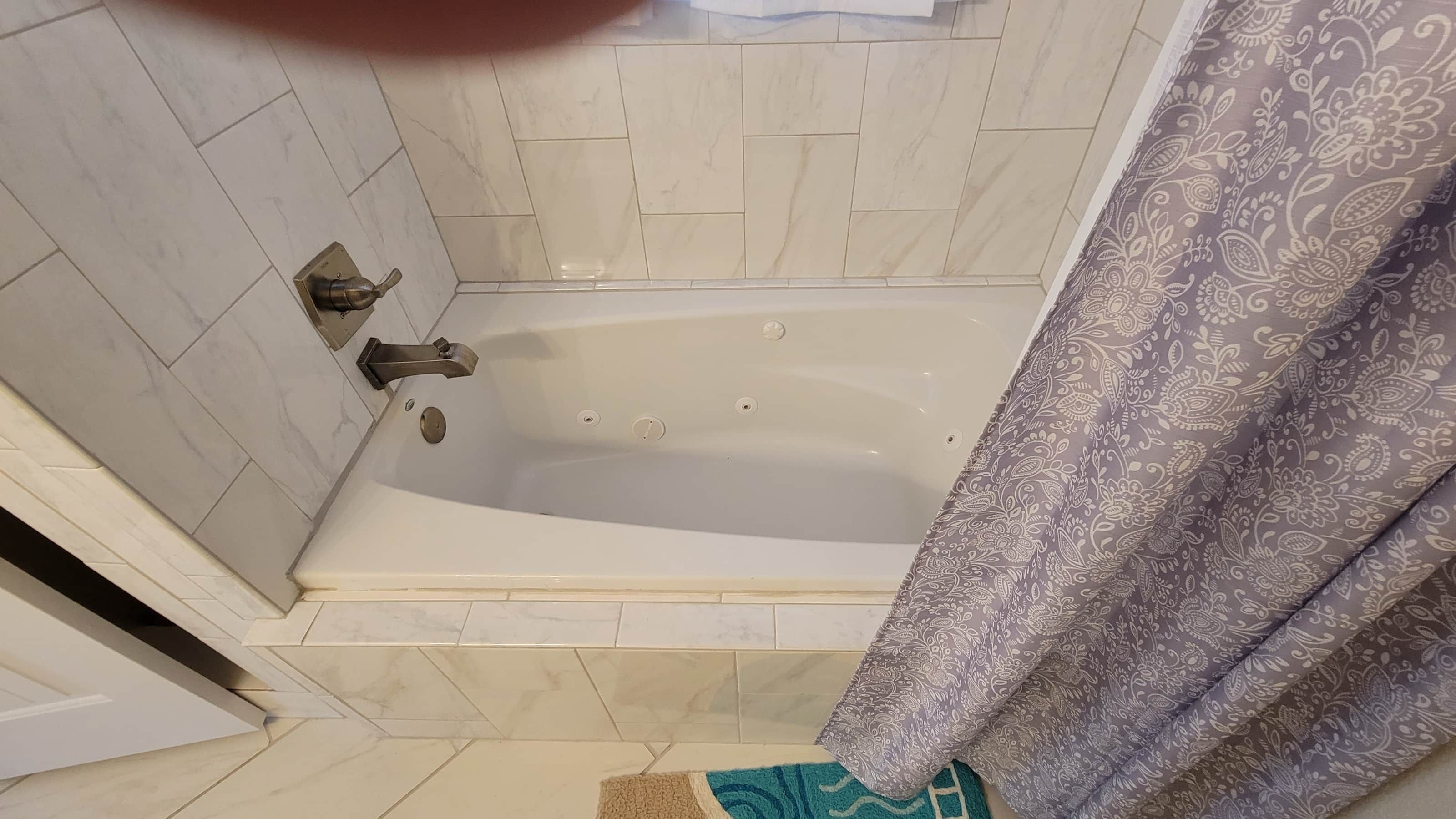 A bathroom with a bathtub, a shower curtain, and tiled walls.
