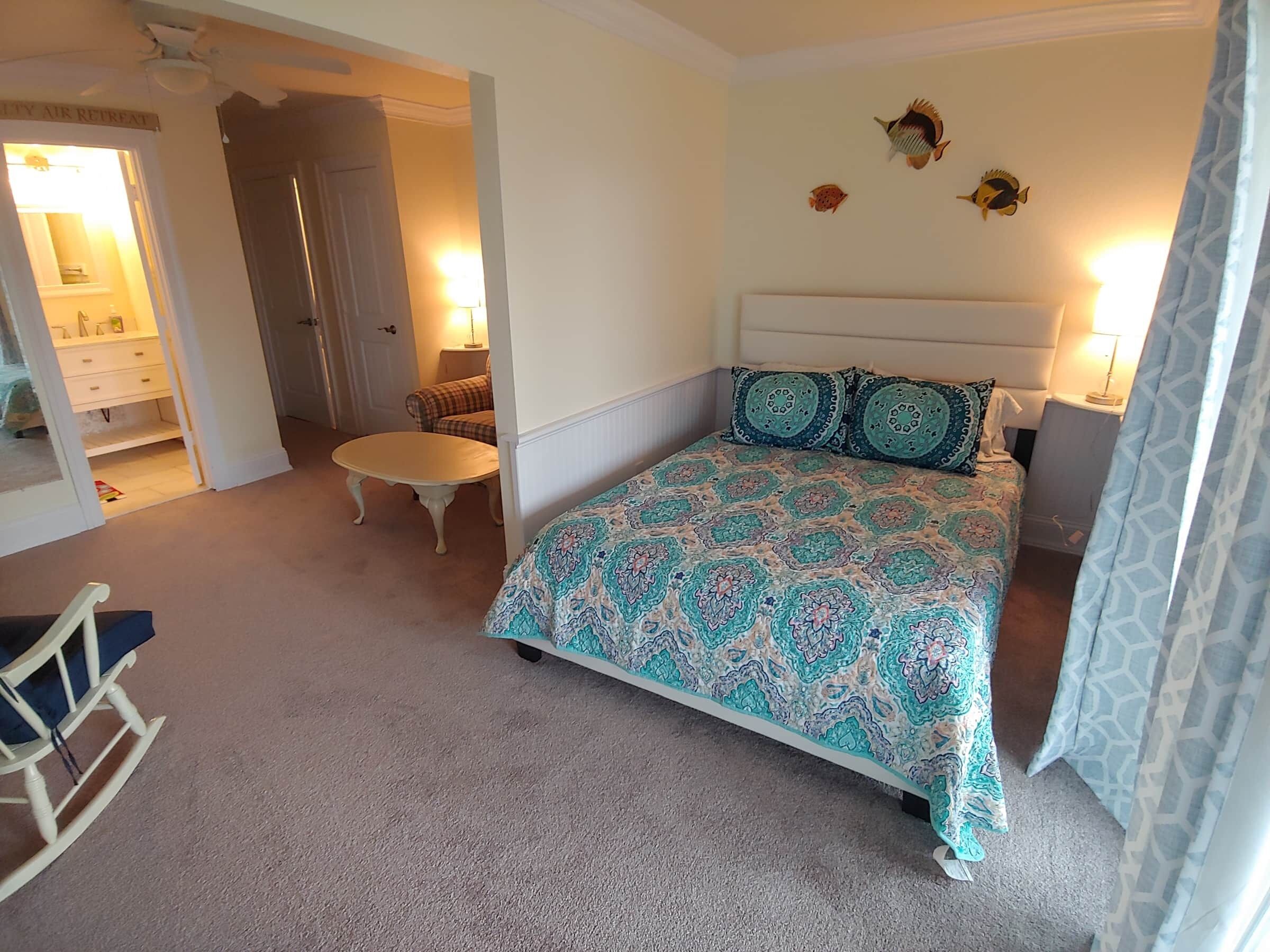 A bedroom with a bed, a nightstand, a chair, and a small table.