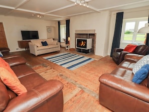 A living room with leather sofas, a fireplace, a television, and a clock on the wall.
