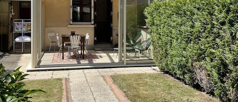 Ein Haus mit überdachter Terrasse, Steinaußenwand und kleinem Garten.