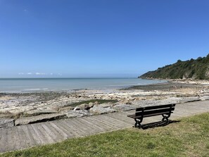 Une plage avec une promenade en bois et un banc.