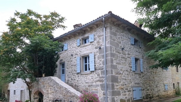A stone building with a rustic appearance, featuring a small porch with wooden barrels and potted plants. - Beautiful 3-bed House in Kotli (Buzet)