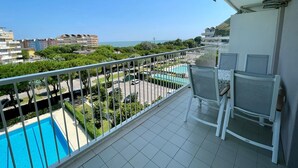 Ein Balkon mit Blick auf einen Swimmingpool, einen Parkplatz und umliegende Gebäude.