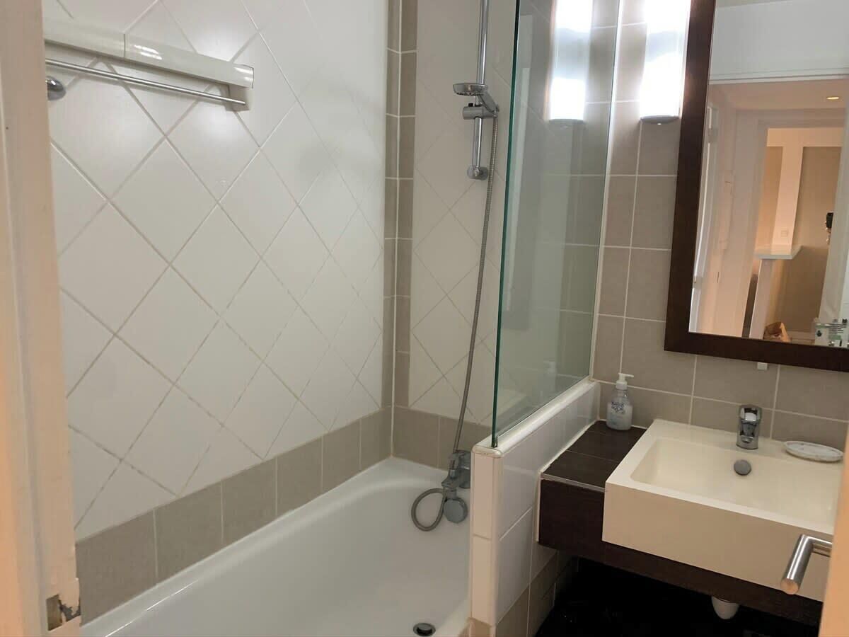 A bathroom with a glass-enclosed shower, a white sink, and a mirror above the sink.