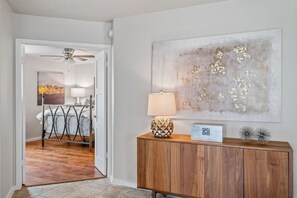 A hallway with a wooden cabinet, a lamp, and a large abstract painting on the wall.