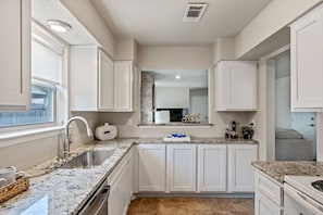 A kitchen with white cabinets, granite countertops, a stainless steel sink, and a built-in oven.