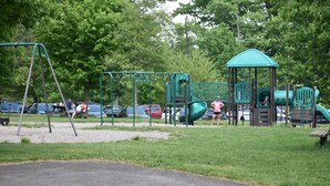 A playground with swings and slides, surrounded by trees and parked cars. - 2 Bedroom Apartment Situated at the Heart of Promised Land State Park (Greentown)