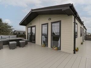 Een modern huis met een overdekte patio, grote ramen en tuinmeubilair.