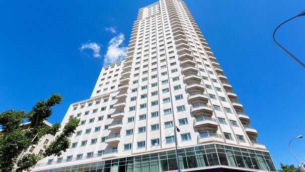 Un grand hôtel moderne à la façade symétrique, doté de larges fenêtres et d’une entrée d’angle bien visible.