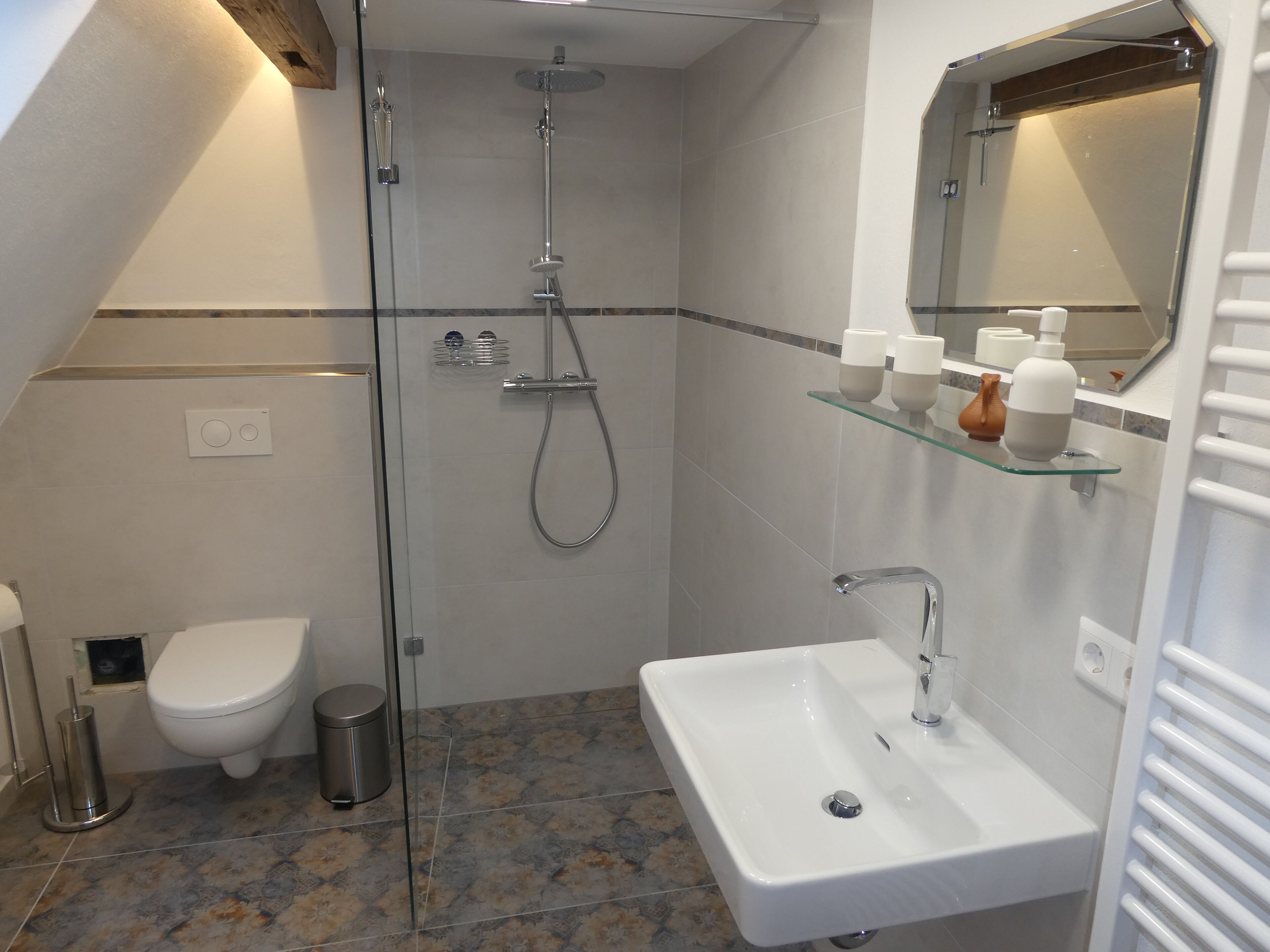 Een moderne badkamer met een douchecabine van glas, een wit wastafelmeubel en een toilet.