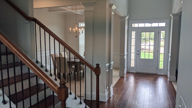 A staircase with wooden railings and a chandelier, leading to a dining area with chairs and a table. - Spacious 5BR 4BA Retreat: The Best Kept Secret in Covington (Covington)