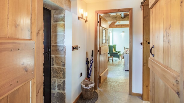 A wooden hallway with stone walls, a basket, and a green chair.