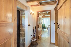 Un pasillo de madera con paredes de piedra, una cesta y una silla verde.