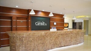 A reception area with a tiled counter, wooden paneling, and pendant lighting. - Hotel Caribe 79 (Barranquilla)