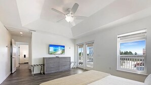 A bedroom with a large bed, a ceiling fan, a TV, a dresser, and a balcony with a view. - 1st Tier Beach Home w/ Heated Pool & Gulf Views! (Port St. Joe)