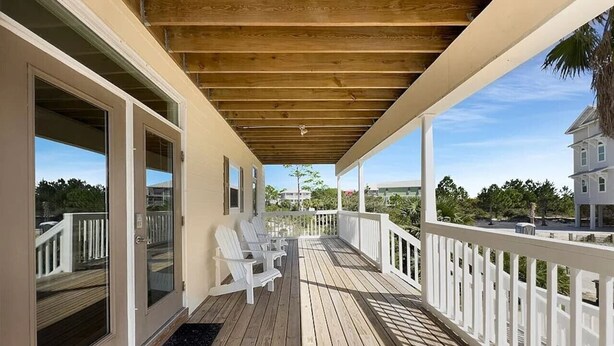 A wooden deck with white railings and chairs, overlooking a residential area. - 1st Tier Beach Home w/ Heated Pool & Gulf Views! (Port St. Joe)