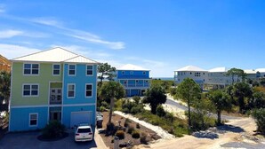 A multi-story residential building with a garage, surrounded by greenery and a clear sky. - 1st Tier Beach Home w/ Heated Pool & Gulf Views! (Port St. Joe)