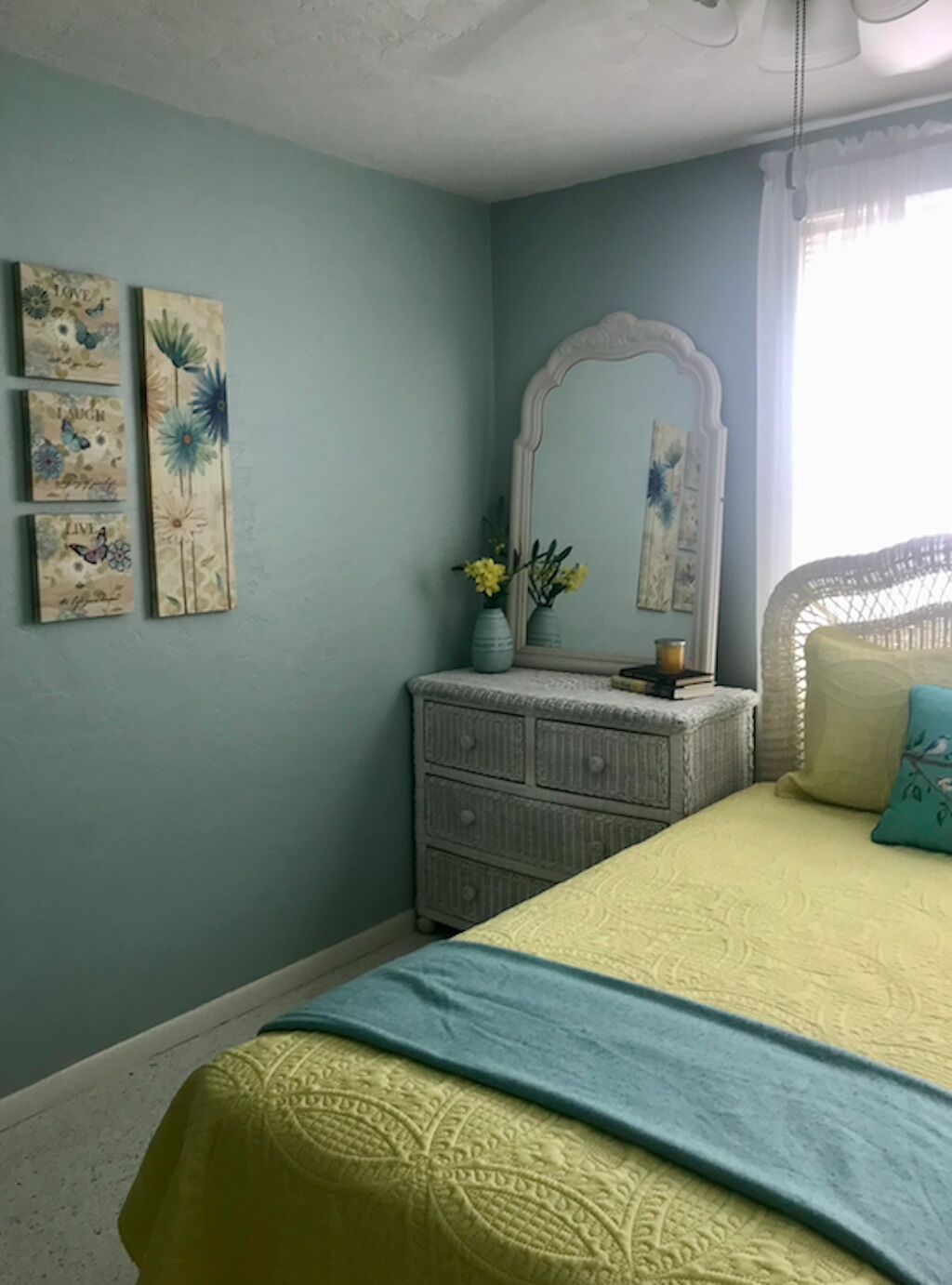A bedroom with a bed, dresser, and wall art.