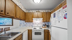 A kitchen with wooden cabinets, a white stove, and a refrigerator.