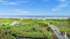 A beach view with a wooden walkway leading to the shore.