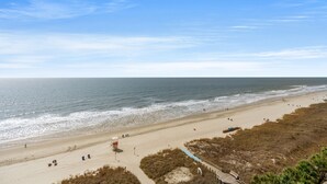 A beach with a lifeguard tower, sandy shore, and a wooden walkway. - Windemere 1006-3BR Oceanfront Ocean Drive (North Myrtle Beach)