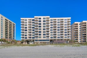 Un hotel de varios pisos con balcones, cerca de una playa.