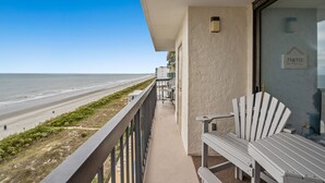 A balcony with a view of the beach, a white chair, and a sign that says "HOME". - Waterpointe II 806-3BR/2BA Oceanfront Condo in Windy Hill (North Myrtle Beach)