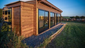 A modern wooden building with large glass windows and a covered patio area.