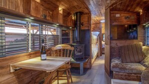 A cozy cabin interior with a wooden interior, a dining table with chairs, a sofa, and a fireplace.