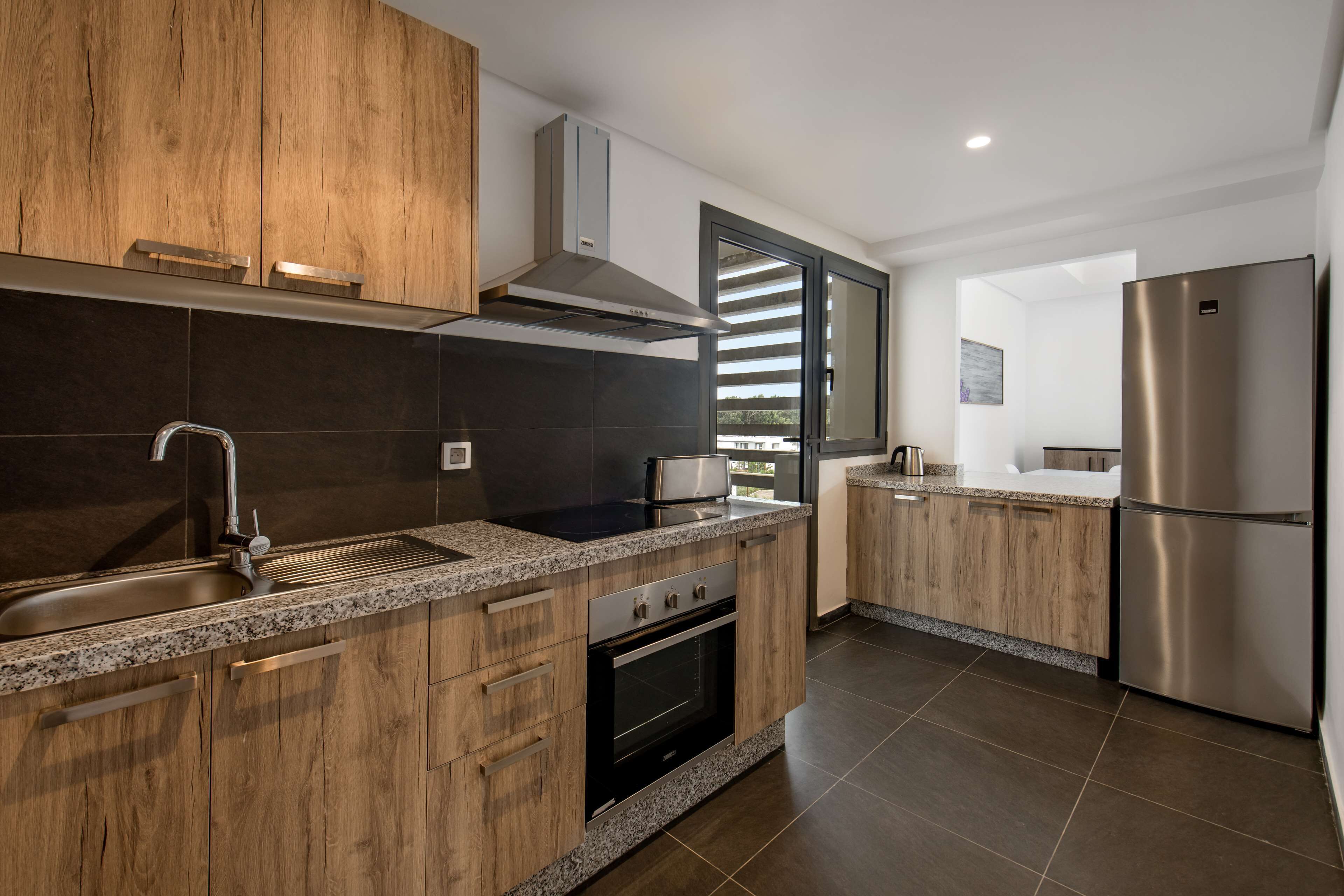 Una cocina moderna con armarios de madera, un refrigerador de acero inoxidable y un horno empotrado.