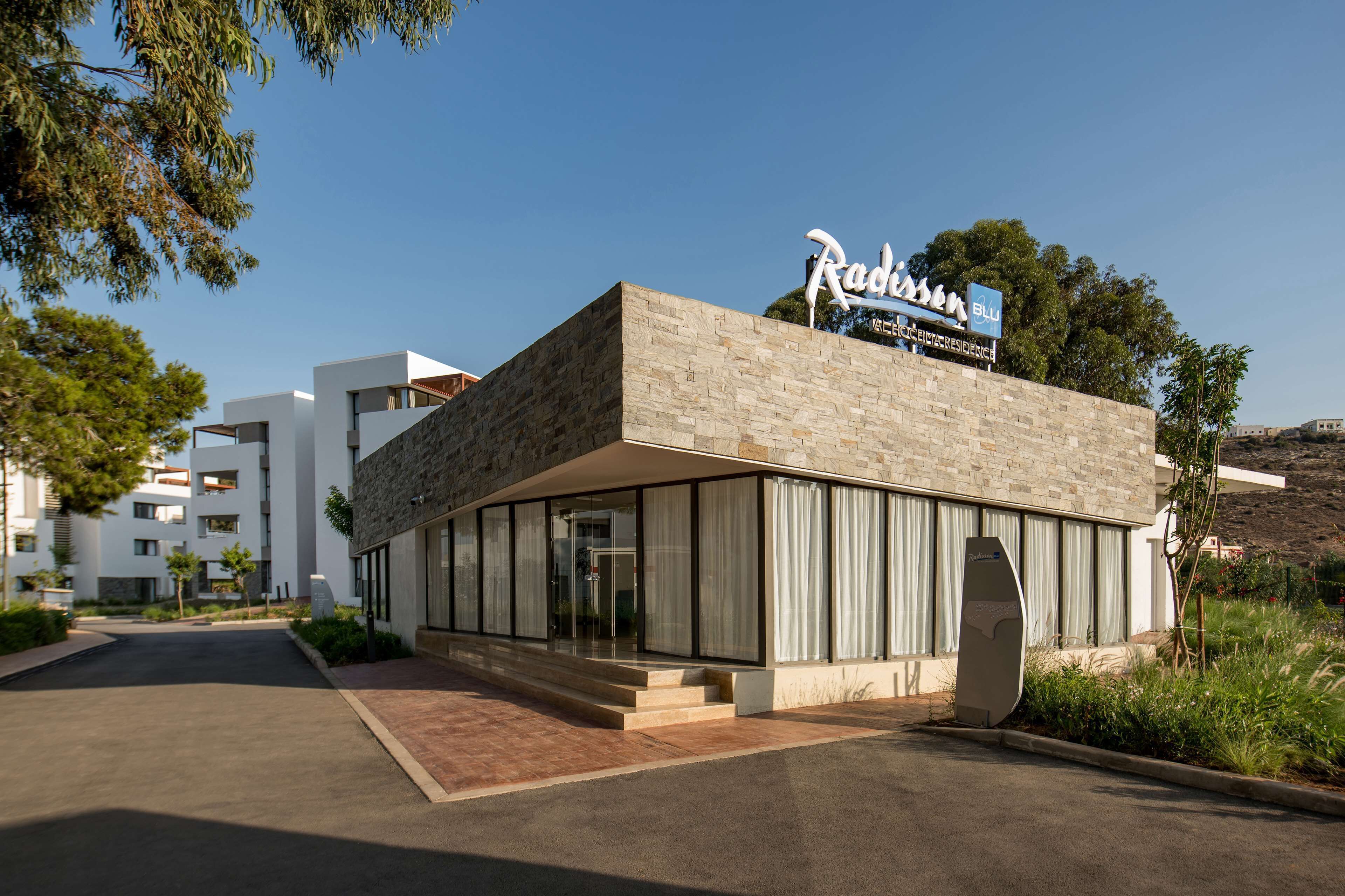 Un hôtel moderne avec une façade en pierre, de grandes fenêtres en verre et une enseigne indiquant « Radisson Blu ».