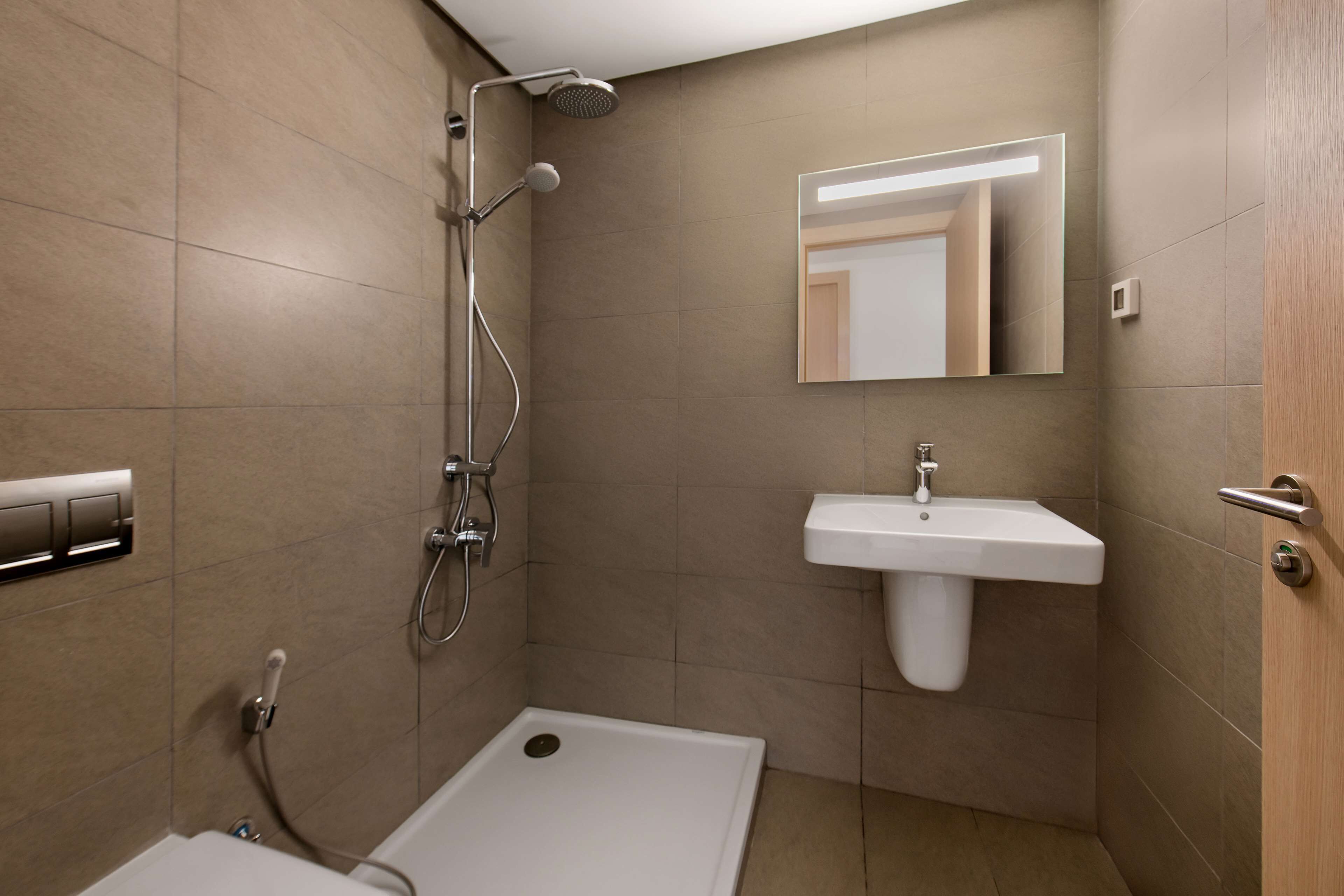 A modern bathroom with a shower, a sink, and a mirror.