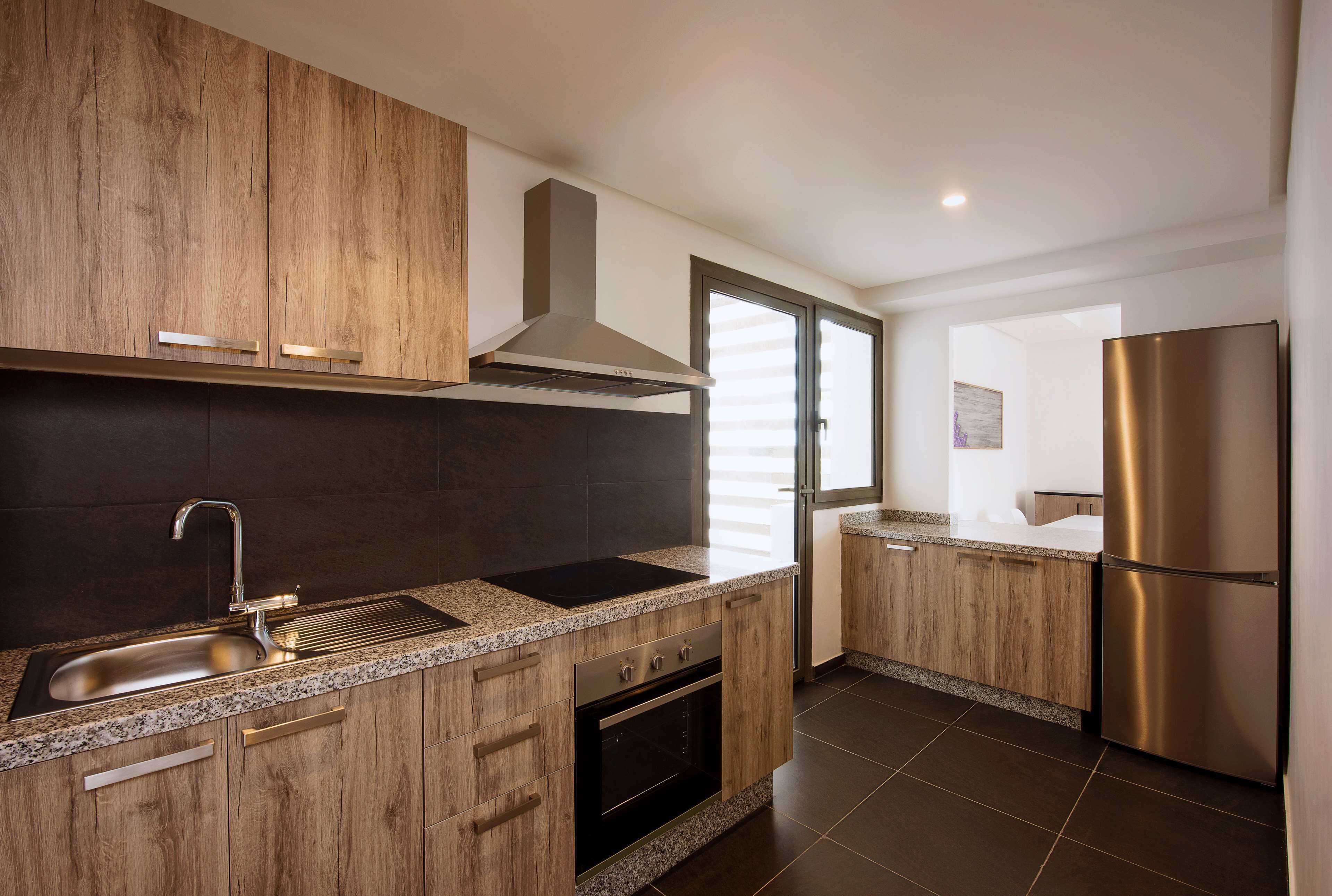 Una cocina moderna con armarios de madera, un lavamanos de acero inoxidable y un horno empotrado.