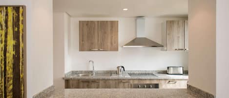 A modern kitchen with granite countertops, wooden cabinets, stainless steel appliances, and recessed ceiling lights.