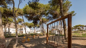A playground with swings and benches, surrounded by trees and buildings in the background. - Radisson Blu Residences Al Hoceima (Ait Youssef Ou Ali)