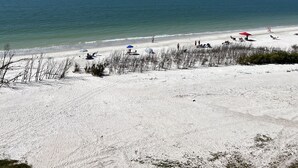 Ein Strand mit weißem Sand, blauem Himmel und ruhiger See.