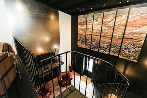A modern interior with a curved staircase, a fireplace, and a large abstract painting on the wall.