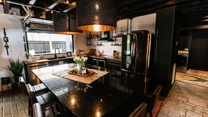 A modern kitchen with a large island, stainless steel appliances, and pendant lighting.
