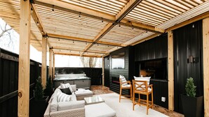 A covered outdoor seating area with a sofa, chairs, and a table.