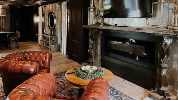A rustic living room with a fireplace, leather sofas, and a flat-screen TV.