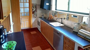 Une cuisine dotée de meubles en bois, d’un lave-vaisselle encastré, d’un évier et d’une fenêtre laissant entrer la lumière naturelle.