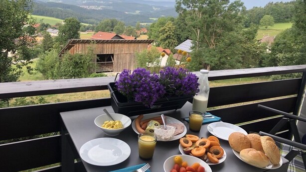 Mesa al aire libre con comida y bebidas, con vistas a un paisaje pintoresco.