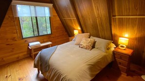 A cozy, wooden-paneled bedroom with a bed, bedside tables, and a bench.