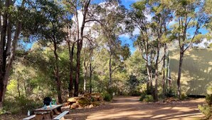 A campsite with picnic tables, a barbecue grill, and a covered area.