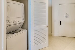 A laundry room with a washing machine and dryer, a door with a window, and a tiled floor. - Opulent Three Bedroom Condo Panoramic Ocean Views (Hollywood)